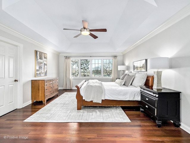 bedroom featuring a raised ceiling, crown molding, dark wood-style floors, and baseboards