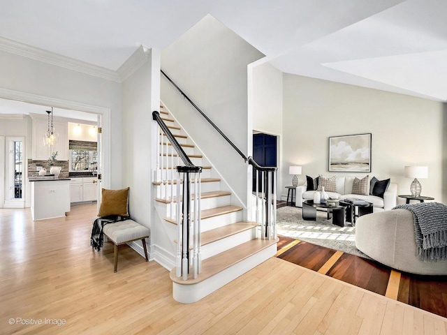 staircase with hardwood / wood-style flooring, lofted ceiling, and ornamental molding