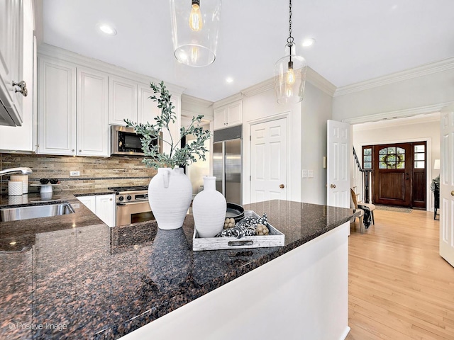 kitchen featuring a sink, stainless steel appliances, light wood-style floors, white cabinetry, and crown molding