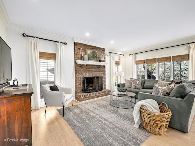 living room with a brick fireplace, recessed lighting, light wood finished floors, and ornamental molding