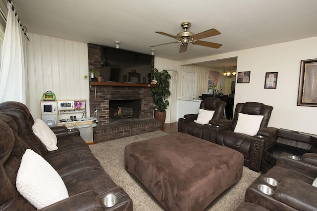 living area with a fireplace and ceiling fan with notable chandelier