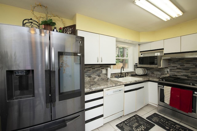 kitchen featuring tasteful backsplash, stainless steel appliances, under cabinet range hood, white cabinetry, and a sink