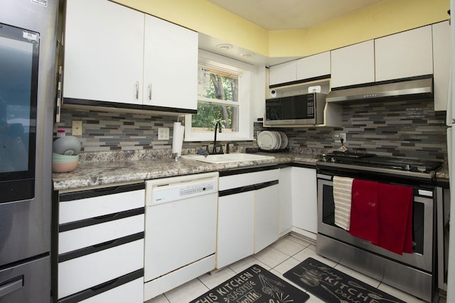 kitchen featuring light tile patterned flooring, under cabinet range hood, a sink, white cabinets, and appliances with stainless steel finishes