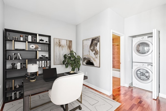 home office with stacked washer and dryer, wood finished floors, and baseboards