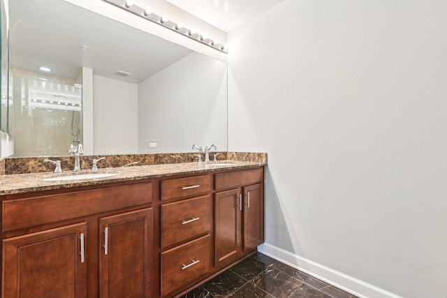 full bath featuring marble finish floor, a sink, baseboards, and double vanity