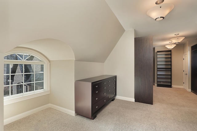 interior space with light carpet, baseboards, and vaulted ceiling