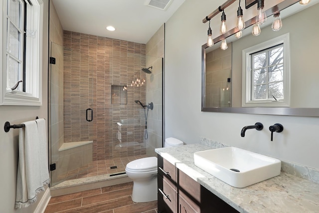 bathroom featuring vanity, visible vents, wood tiled floor, a stall shower, and toilet