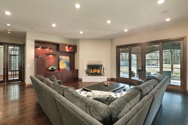 living room with baseboards, recessed lighting, a lit fireplace, dark wood-type flooring, and french doors