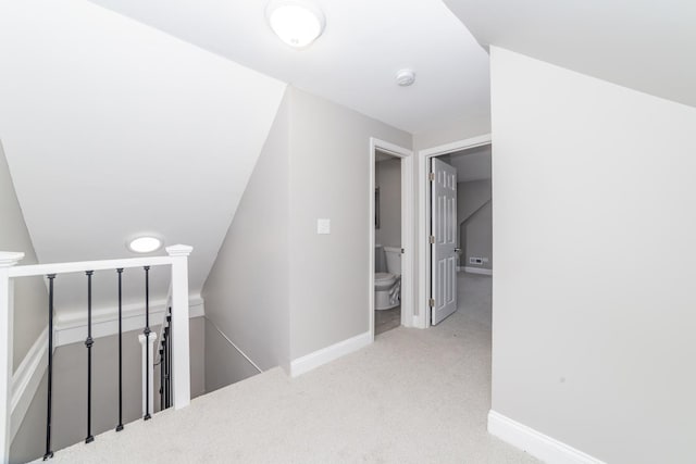 hallway featuring carpet floors, baseboards, and an upstairs landing