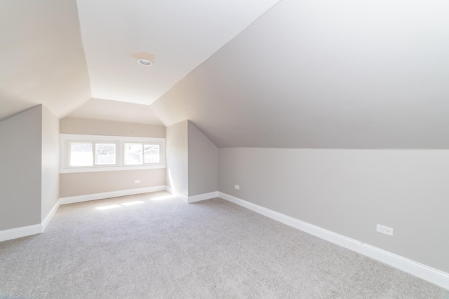 bonus room featuring lofted ceiling, light colored carpet, and baseboards