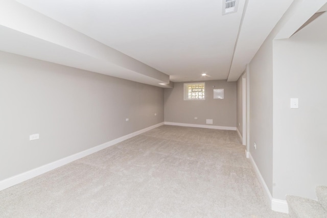 below grade area featuring light carpet, stairway, baseboards, and visible vents