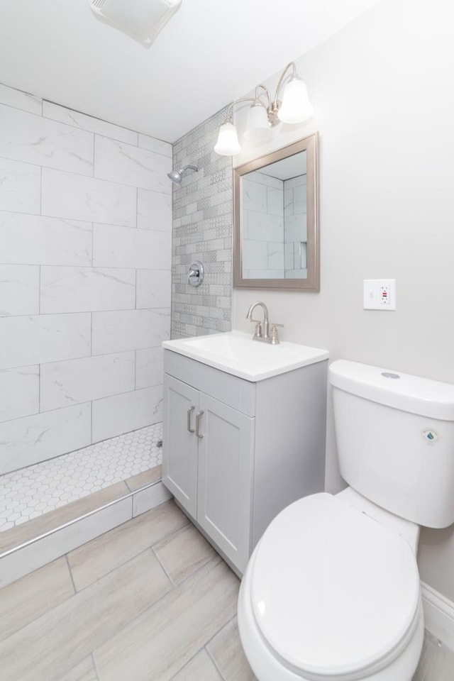 full bath with tiled shower, vanity, and toilet