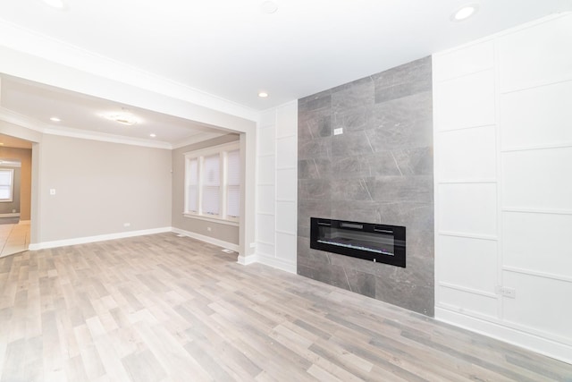 unfurnished living room featuring light wood-style floors, baseboards, crown molding, and a tile fireplace