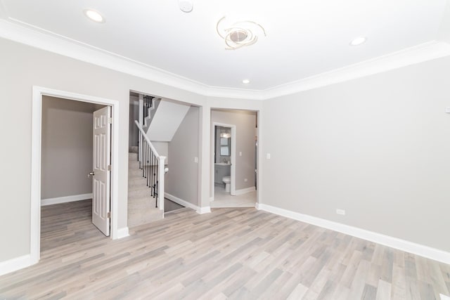 spare room featuring light wood-style floors, baseboards, stairs, and ornamental molding