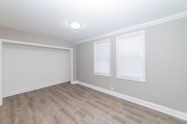 spare room featuring ornamental molding, light wood-type flooring, and baseboards