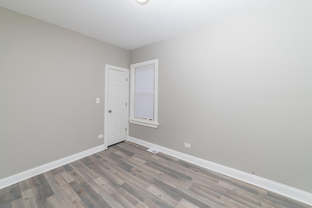 spare room featuring visible vents, baseboards, and wood finished floors