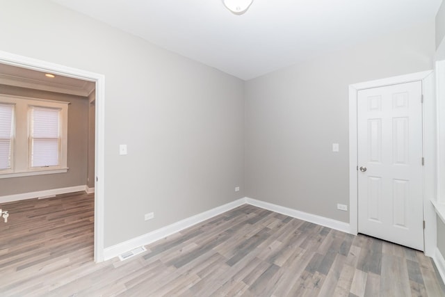 spare room with visible vents, baseboards, and wood finished floors