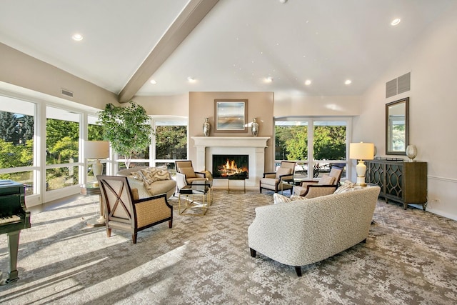 living room with visible vents, beam ceiling, a lit fireplace, and high vaulted ceiling