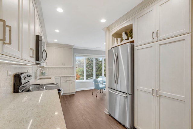 kitchen featuring light stone counters, tasteful backsplash, wood finished floors, appliances with stainless steel finishes, and crown molding