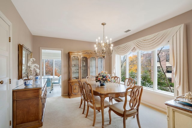 dining area with a chandelier, visible vents, light carpet, and baseboards