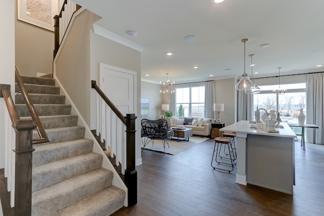 interior space with dark wood-style floors, a chandelier, a kitchen breakfast bar, and crown molding