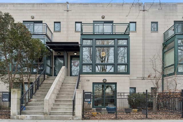 view of exterior entry with a balcony and fence