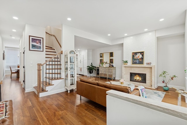 living area featuring recessed lighting, stairway, wood finished floors, and a fireplace