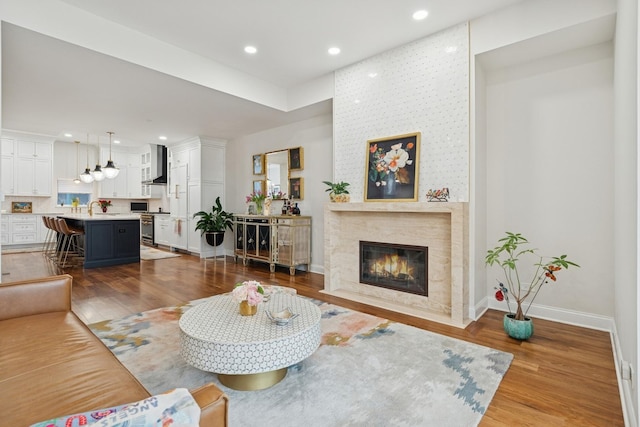 living area featuring a high end fireplace, recessed lighting, baseboards, and wood finished floors