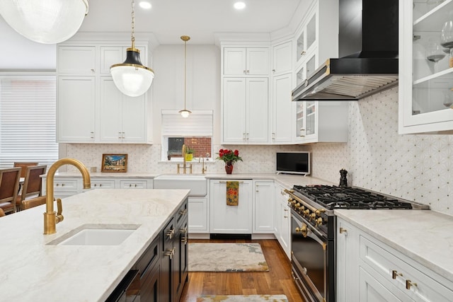 kitchen featuring white cabinets, high end stainless steel range oven, wall chimney range hood, and a sink