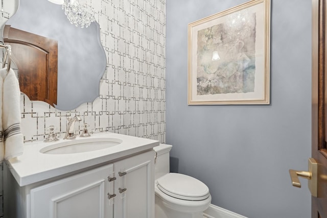 half bath featuring vanity, toilet, and baseboards