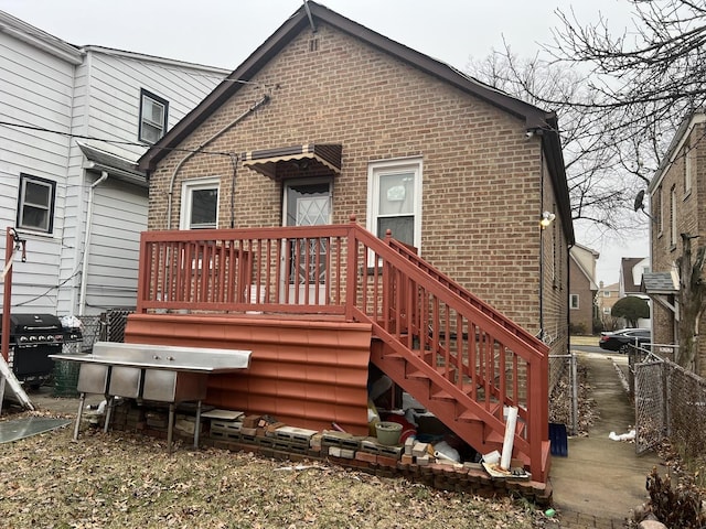 rear view of property with brick siding and fence