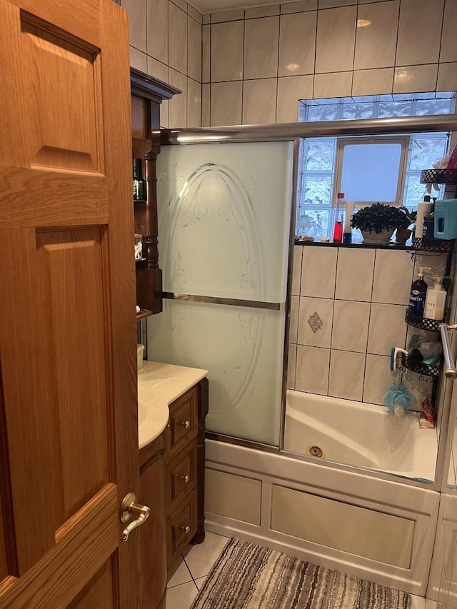 bathroom with tile patterned flooring, vanity, and bath / shower combo with glass door