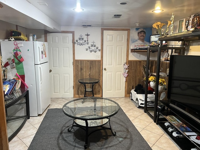 kitchen featuring light tile patterned floors, wooden walls, visible vents, wainscoting, and freestanding refrigerator