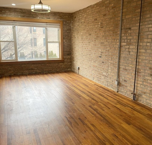 spare room with wood-type flooring and brick wall