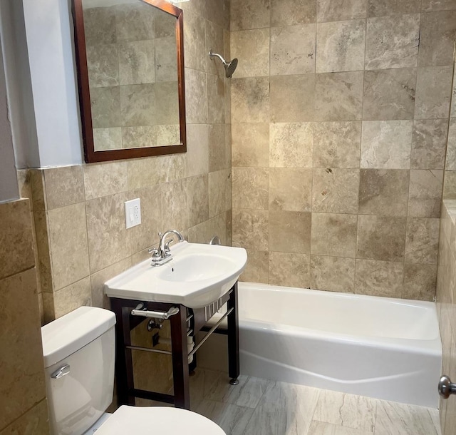 bathroom featuring marble finish floor, bathtub / shower combination, toilet, and tile walls