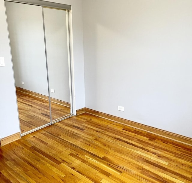 unfurnished bedroom with a closet, wood finished floors, and baseboards