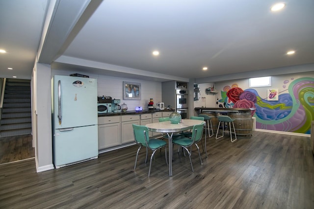 dining area featuring recessed lighting, stairway, dark wood finished floors, and a dry bar