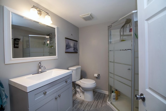 bathroom with vanity, a shower stall, toilet, and visible vents