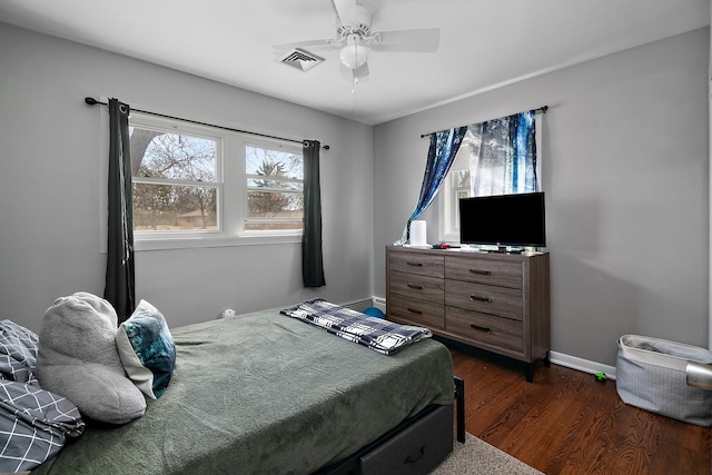 bedroom featuring visible vents, a ceiling fan, a baseboard heating unit, dark wood-style floors, and baseboards