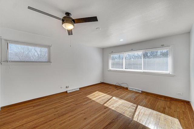 spare room featuring ceiling fan, wood finished floors, visible vents, and baseboards