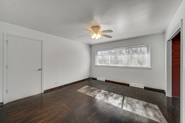 empty room featuring hardwood / wood-style floors, visible vents, and baseboards