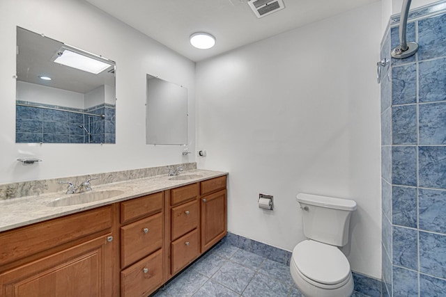 full bathroom featuring toilet, a sink, visible vents, and a tile shower