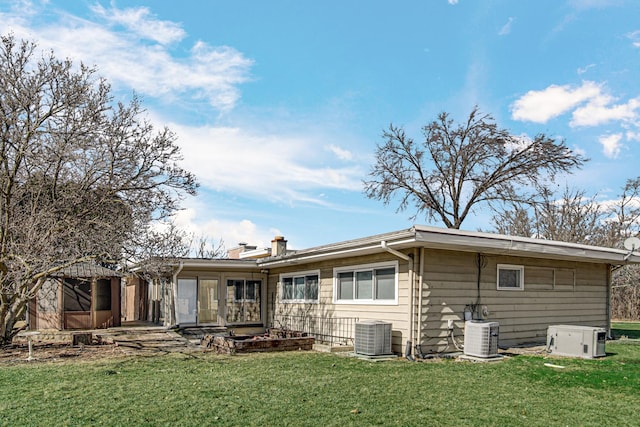 rear view of house featuring a chimney, central AC unit, and a yard