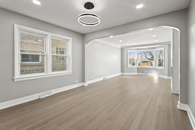 interior space featuring arched walkways, visible vents, baseboards, and wood finished floors