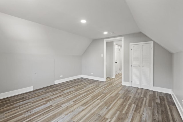 additional living space featuring vaulted ceiling, baseboards, and wood finished floors