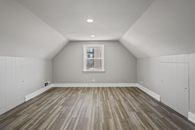 additional living space featuring lofted ceiling, visible vents, baseboards, and wood finished floors