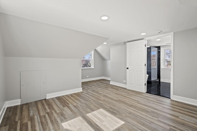 additional living space with baseboards, vaulted ceiling, wood finished floors, and recessed lighting