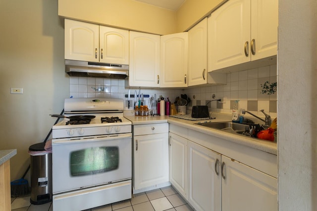 kitchen with backsplash, under cabinet range hood, white gas stove, light tile patterned flooring, and a sink