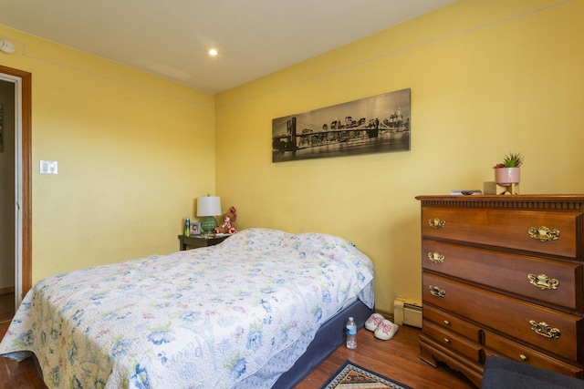 bedroom with a baseboard heating unit and dark wood-style flooring