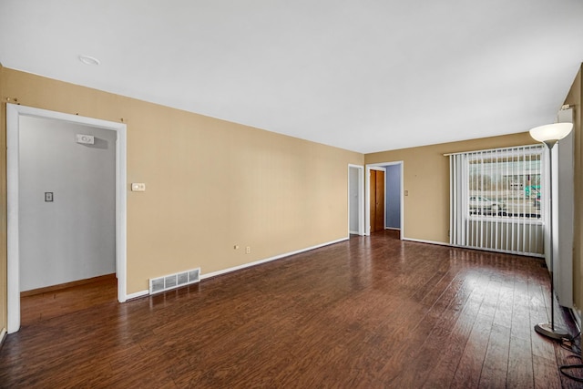 spare room with baseboards, visible vents, and wood finished floors